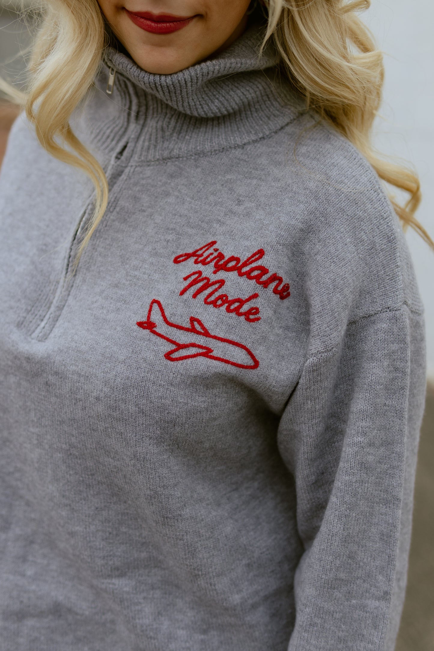 Grey sweater with Airplane Mode embroidered on the corner in red