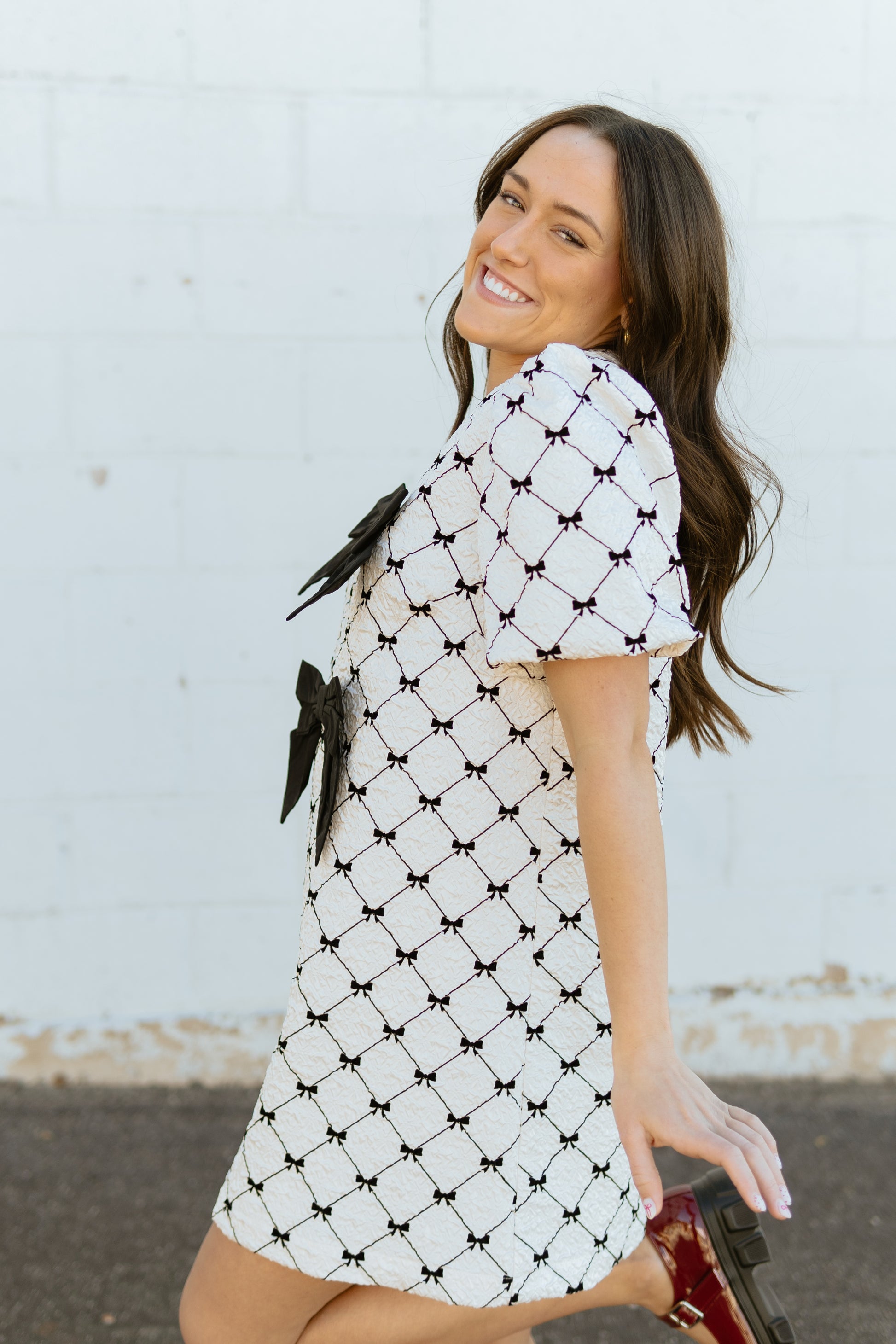 White mini dress with black bow print and two large bows down the front