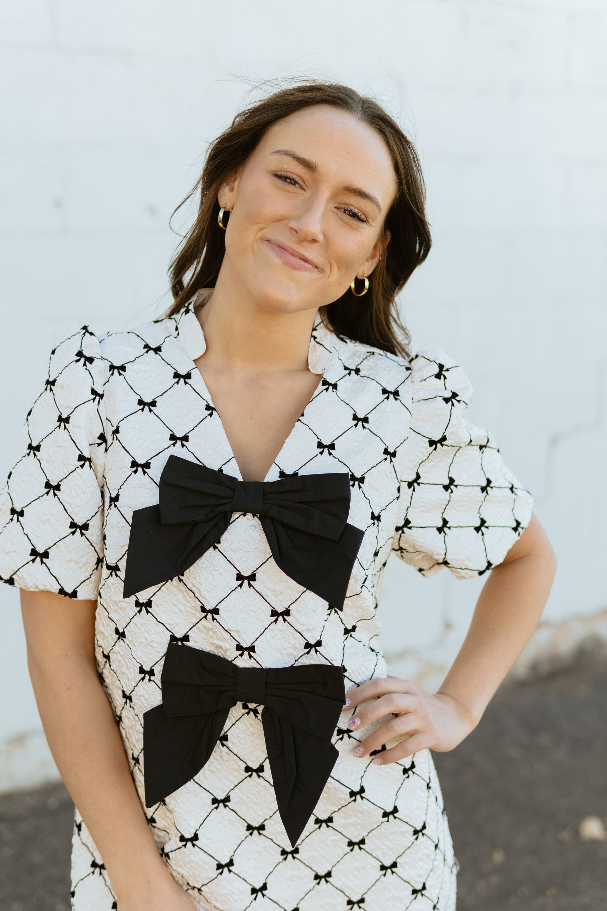 White mini dress with black bow print and two large bows down the front