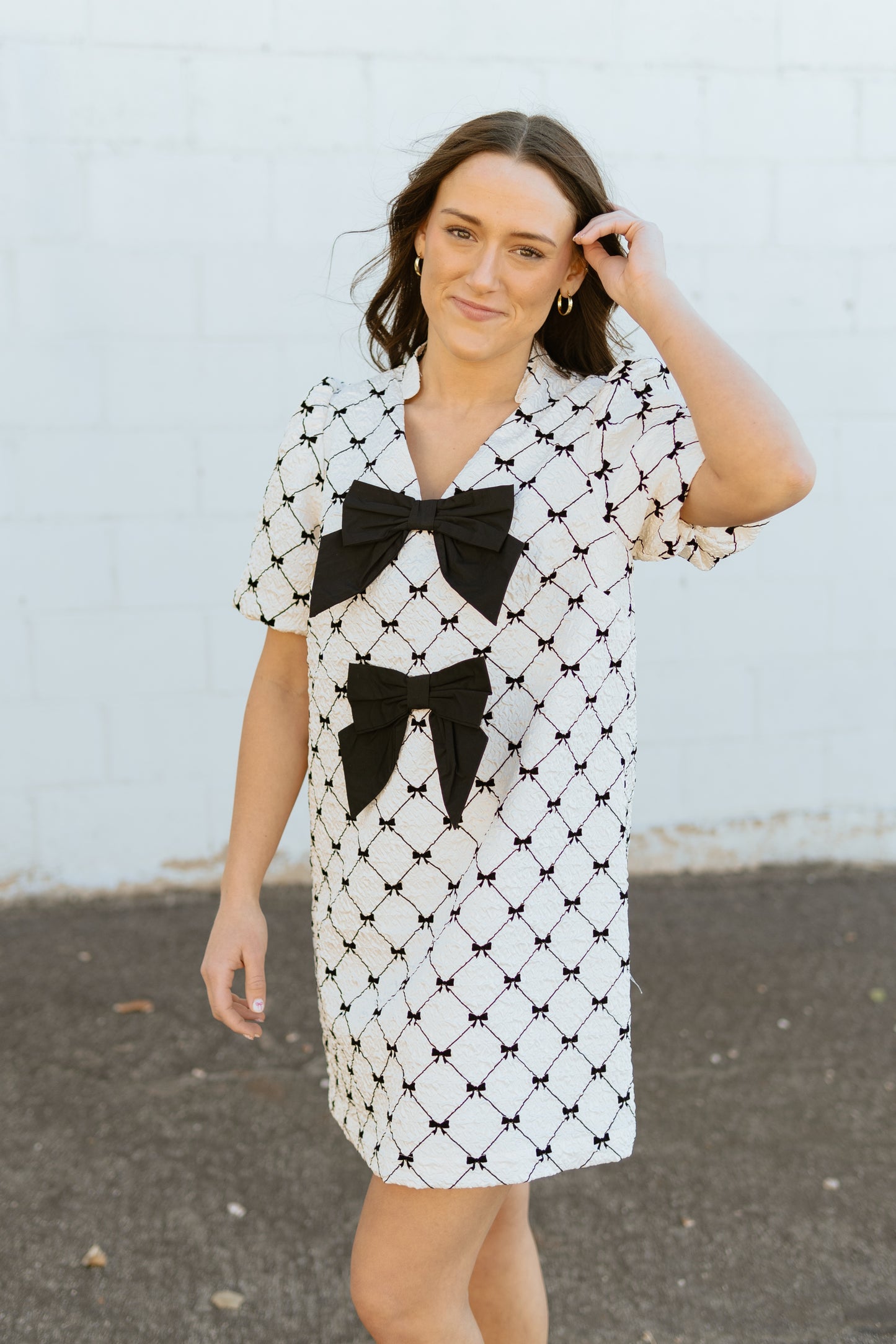 White mini dress with black bow print and two large bows down the front