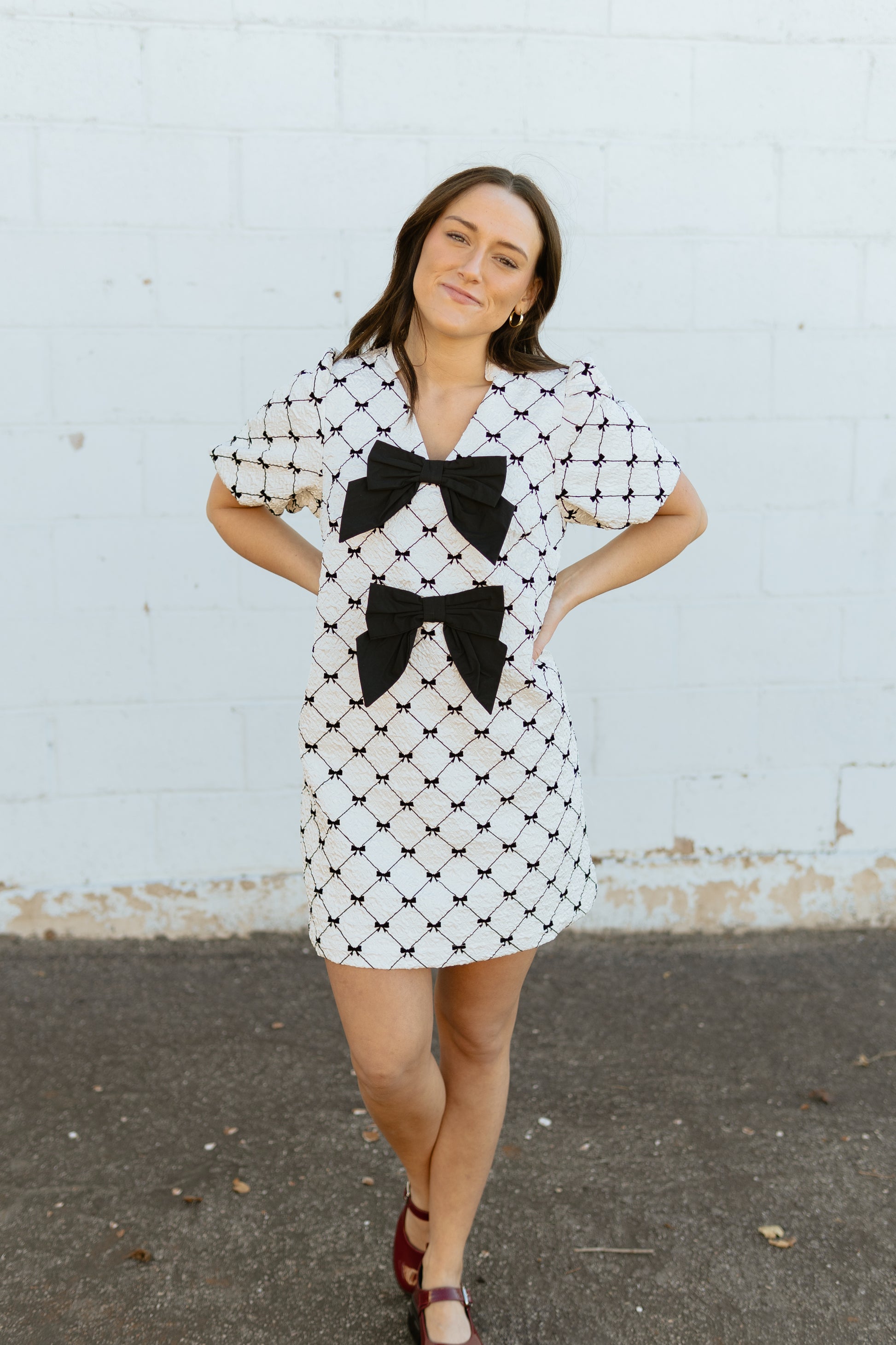 White mini dress with black bow print and two large bows down the front