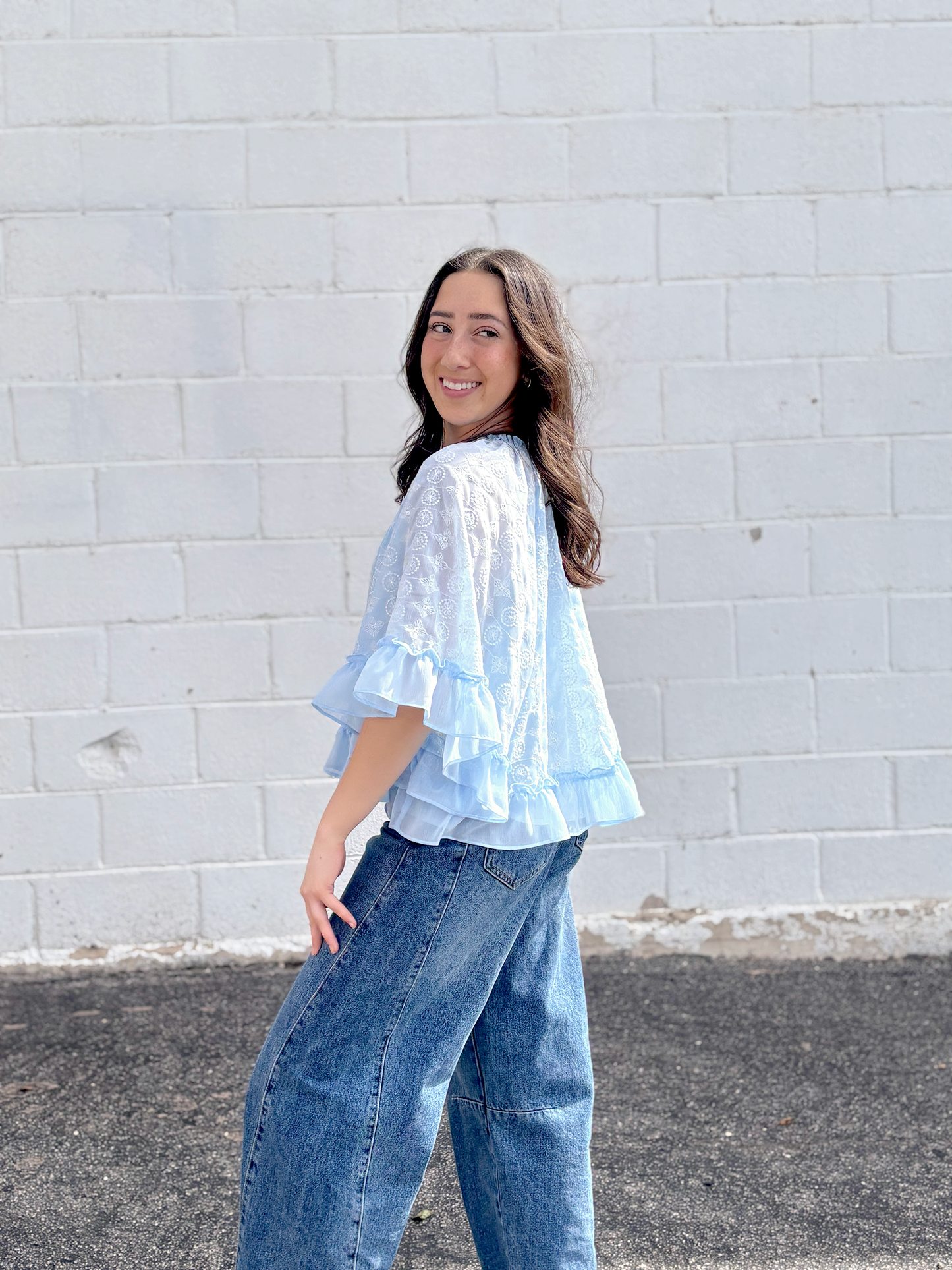 Light blue cape top with white embroidered pattern over top and ruffles along the sleeves and bottom of top