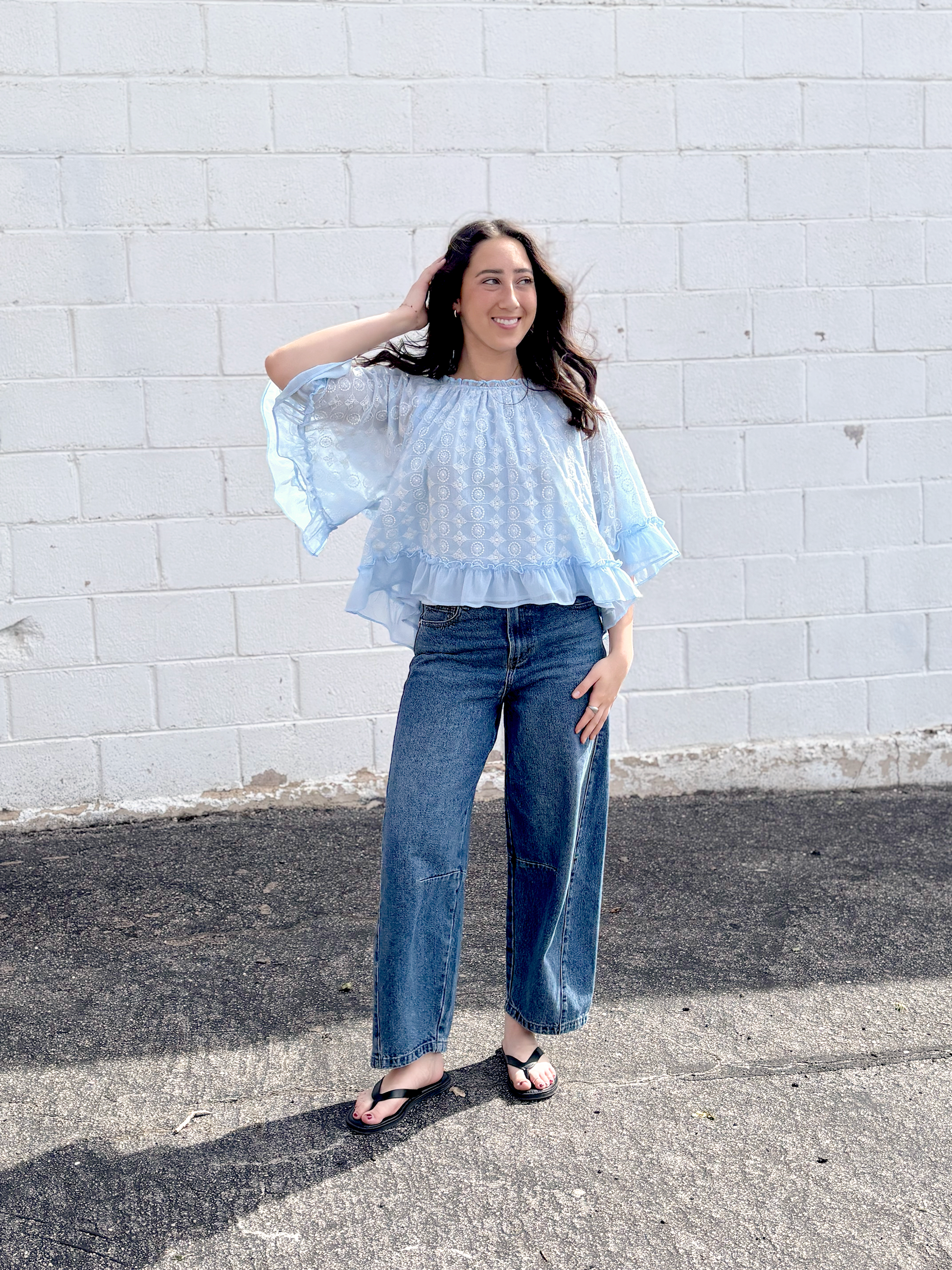 Light blue cape top with white embroidered pattern over top and ruffles along the sleeves and bottom of top