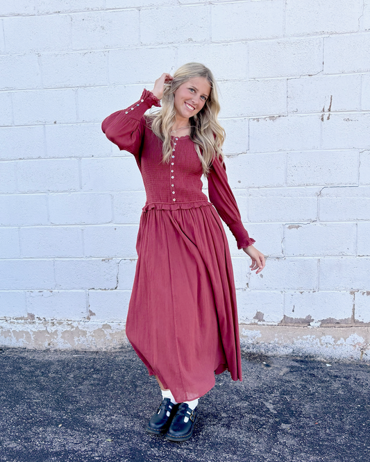 Rust colored dress with ruched bodice and long balloon sleeves and decorative buttons up the front and on the sleeve