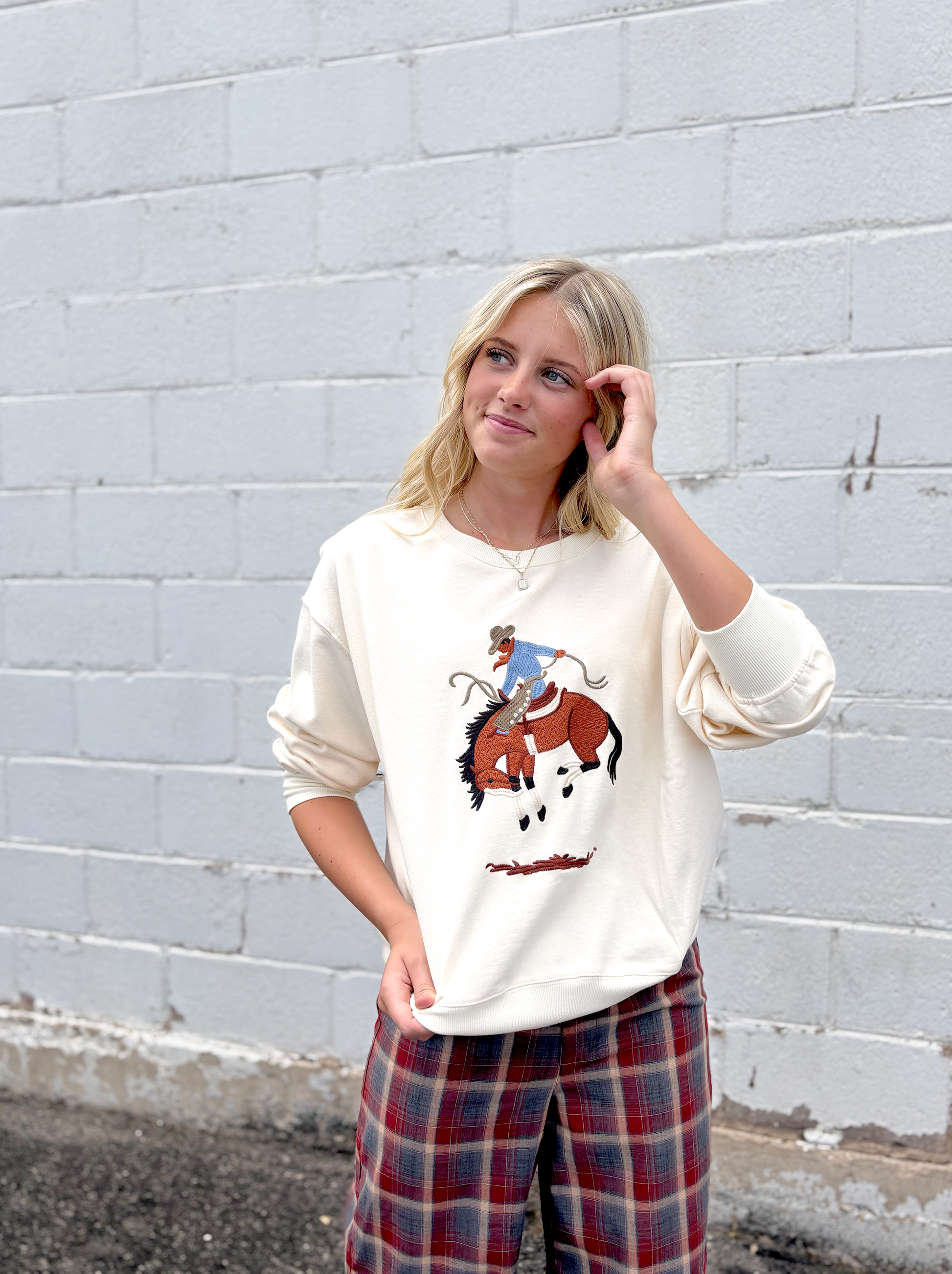 Cream colored sweater with a cowboy embroidered on the front
