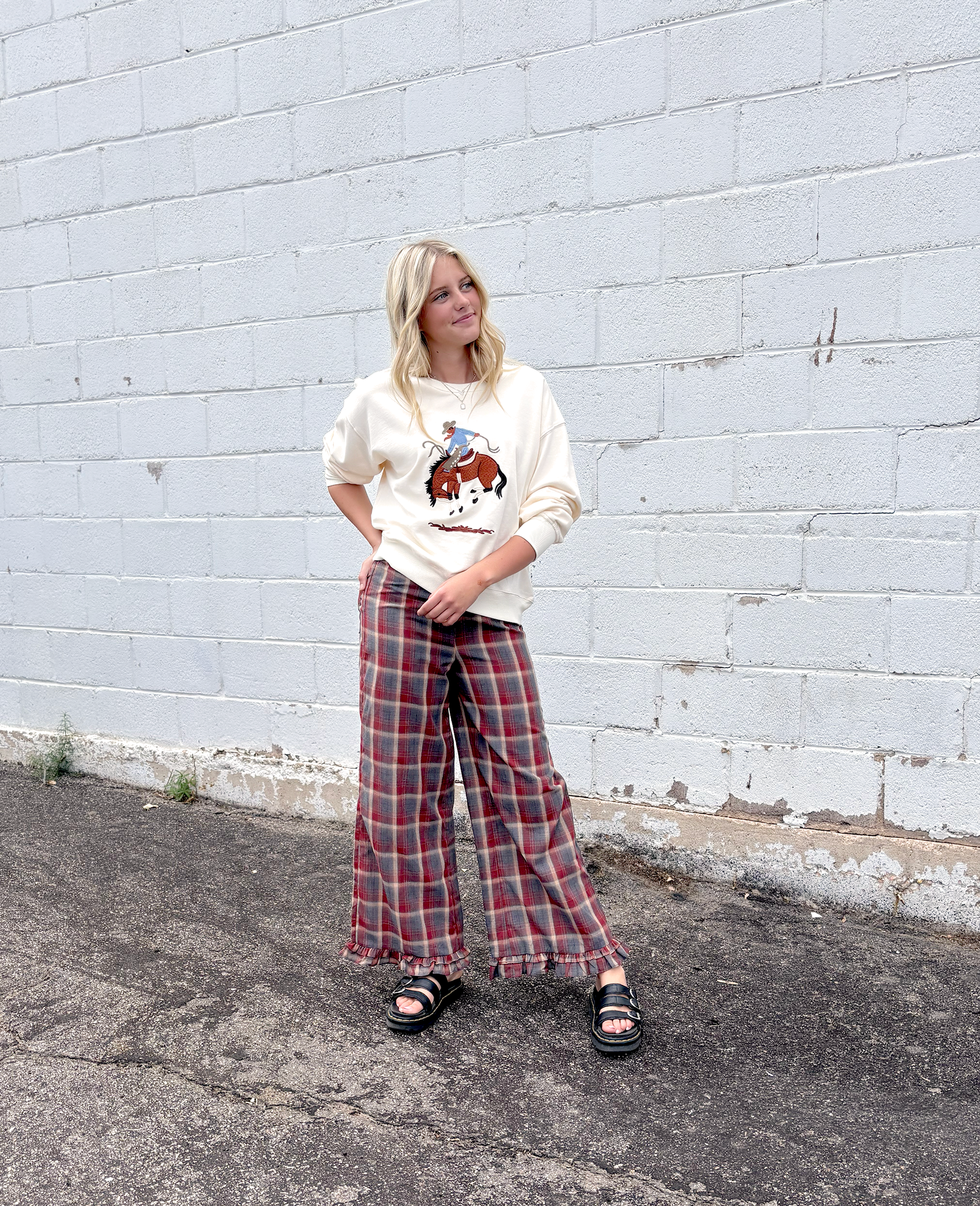 Cream colored sweater with a cowboy embroidered on the front