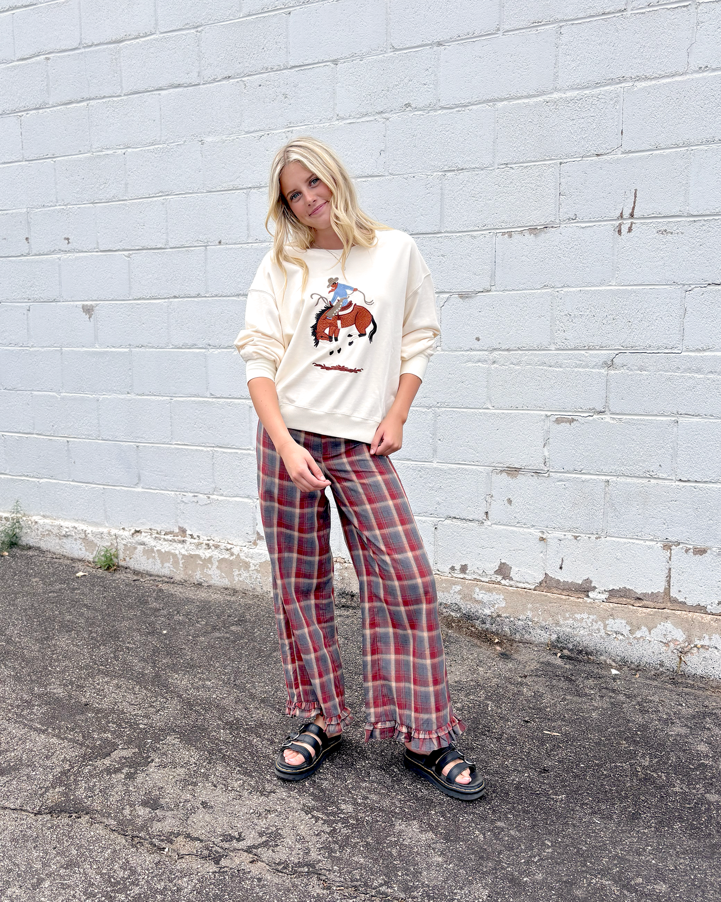 Cream colored sweater with a cowboy embroidered on the front