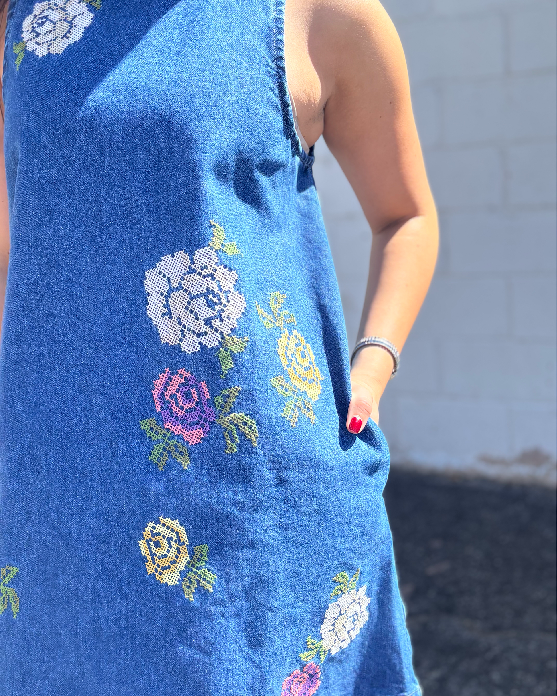 Cute short sleeveless denim dress with embroidered flowers on the front