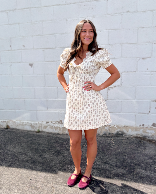 Ivory mini dress with puff sleeves and a v-neckline and a dark brown floral pattern