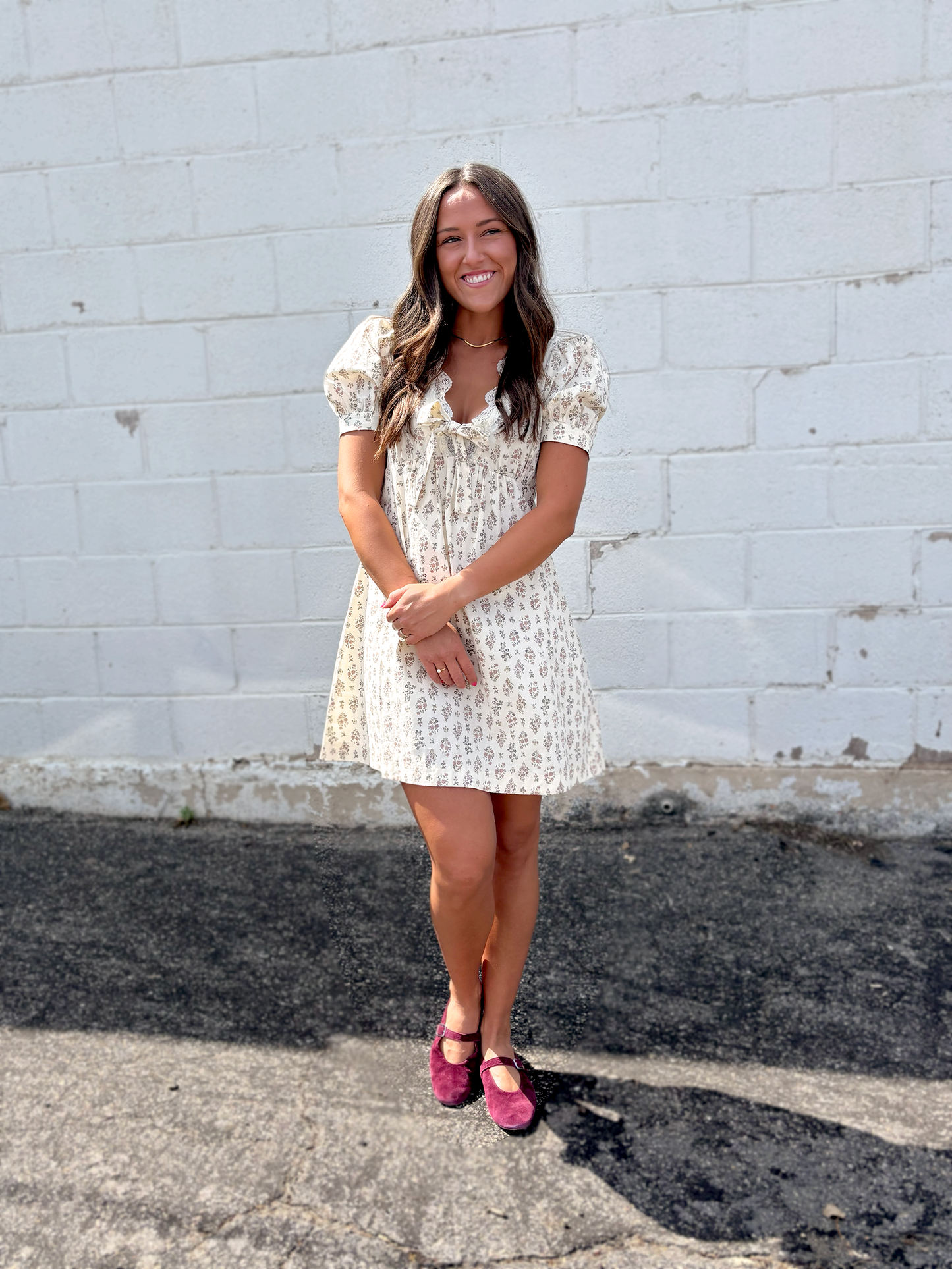 Ivory mini dress with puff sleeves and a v-neckline and a dark brown floral pattern