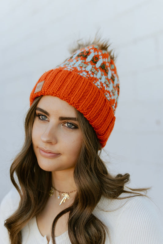 Rust colored beanie with multi color knit pattern