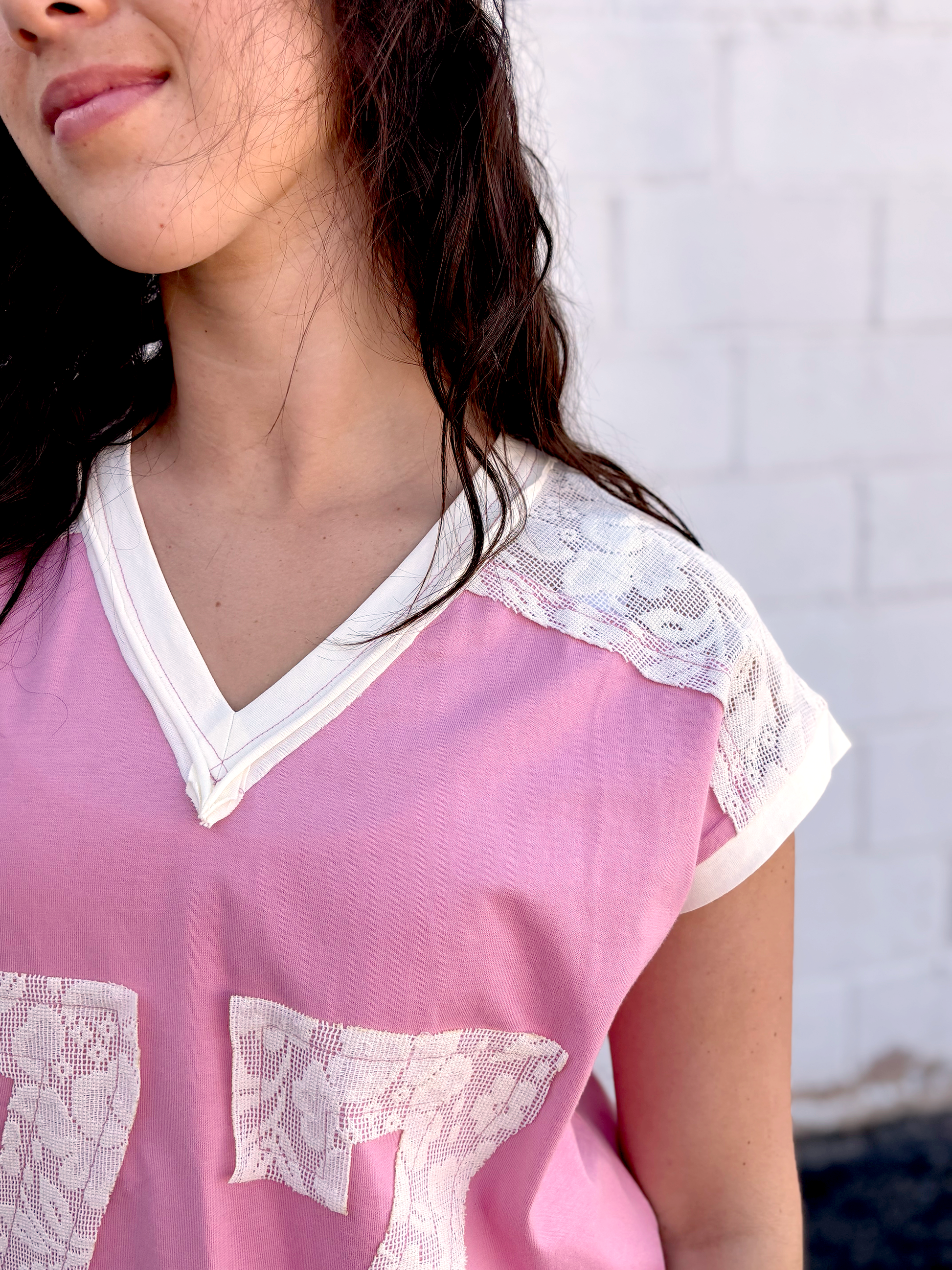 Cute pink tee shirt with lace along the shoulders and a lace 77 appliquéd on the front