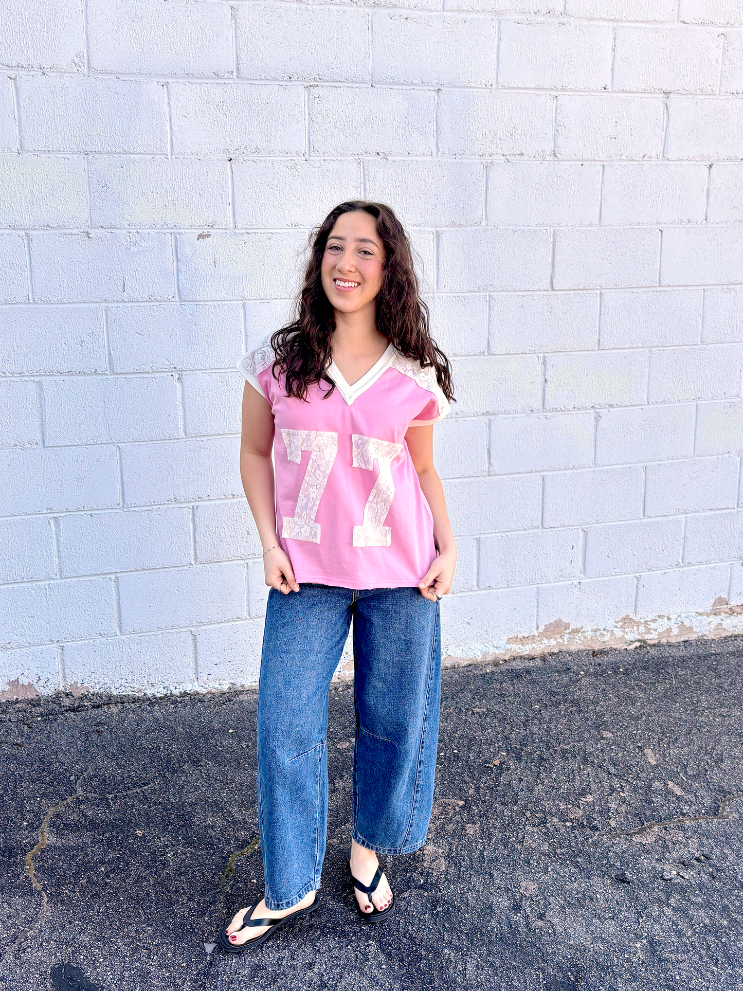 Cute pink tee shirt with lace along the shoulders and a lace 77 appliquéd on the front