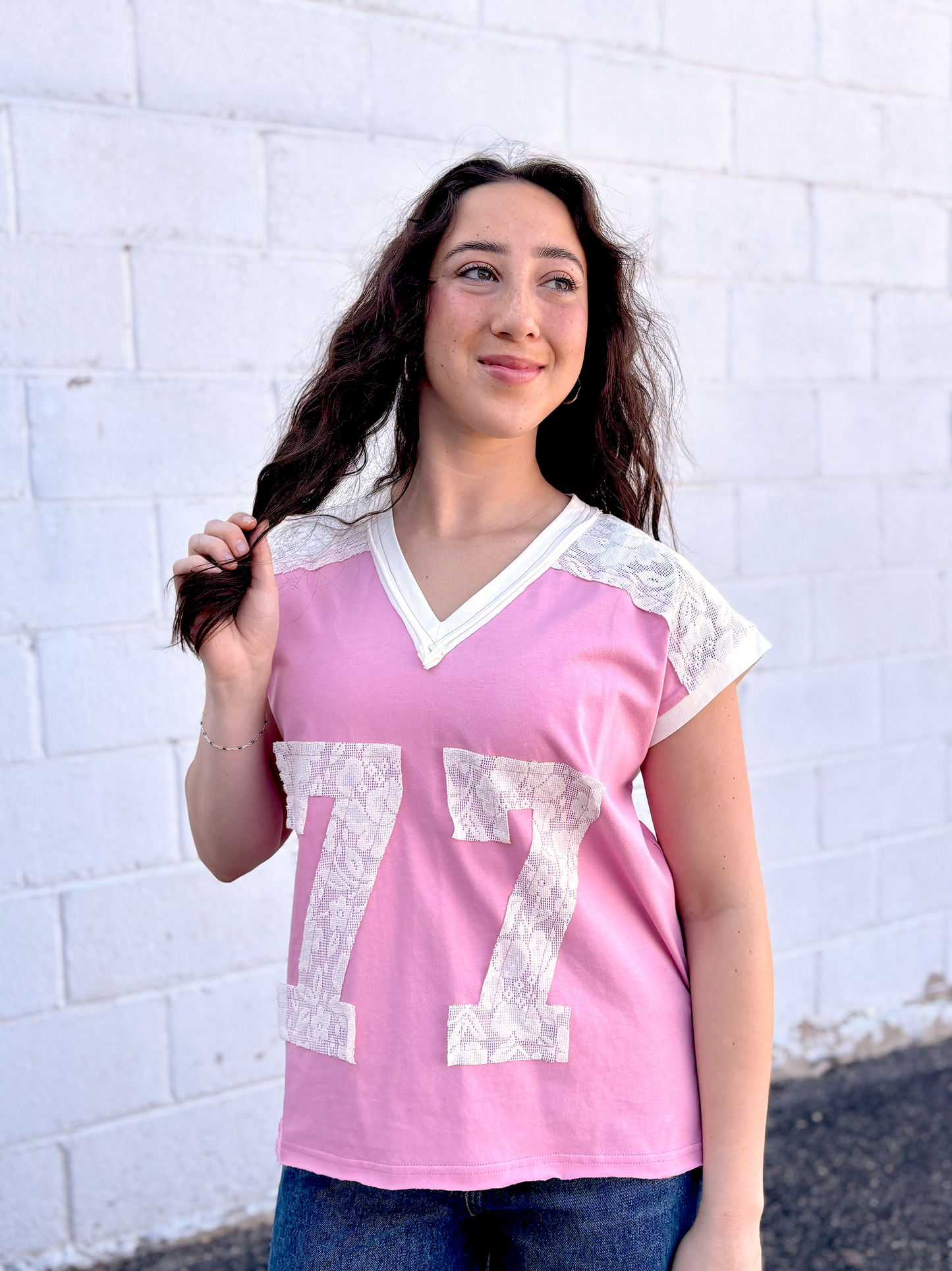 Cute pink tee shirt with lace along the shoulders and a lace 77 appliquéd on the front