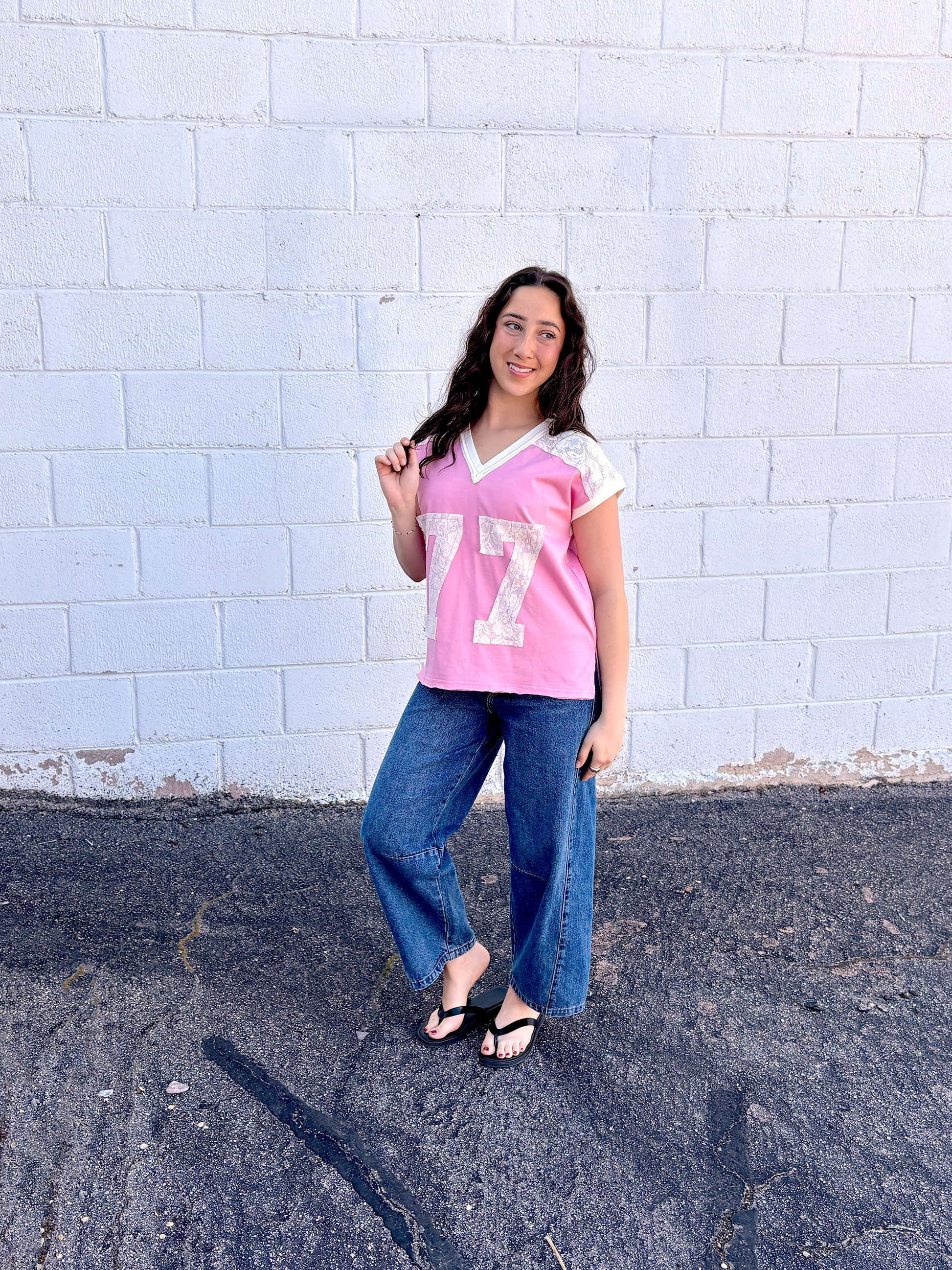 Cute pink tee shirt with lace along the shoulders and a lace 77 appliquéd on the front
