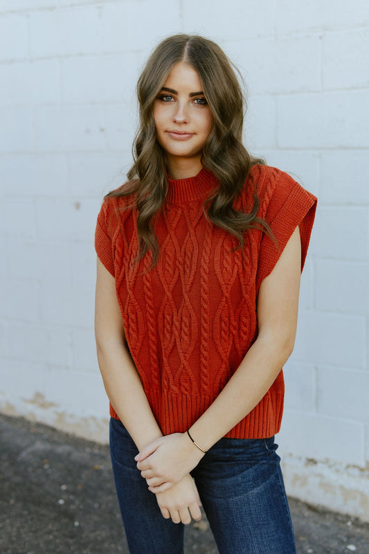 Rust red sleeveless sweater with cable knit texture