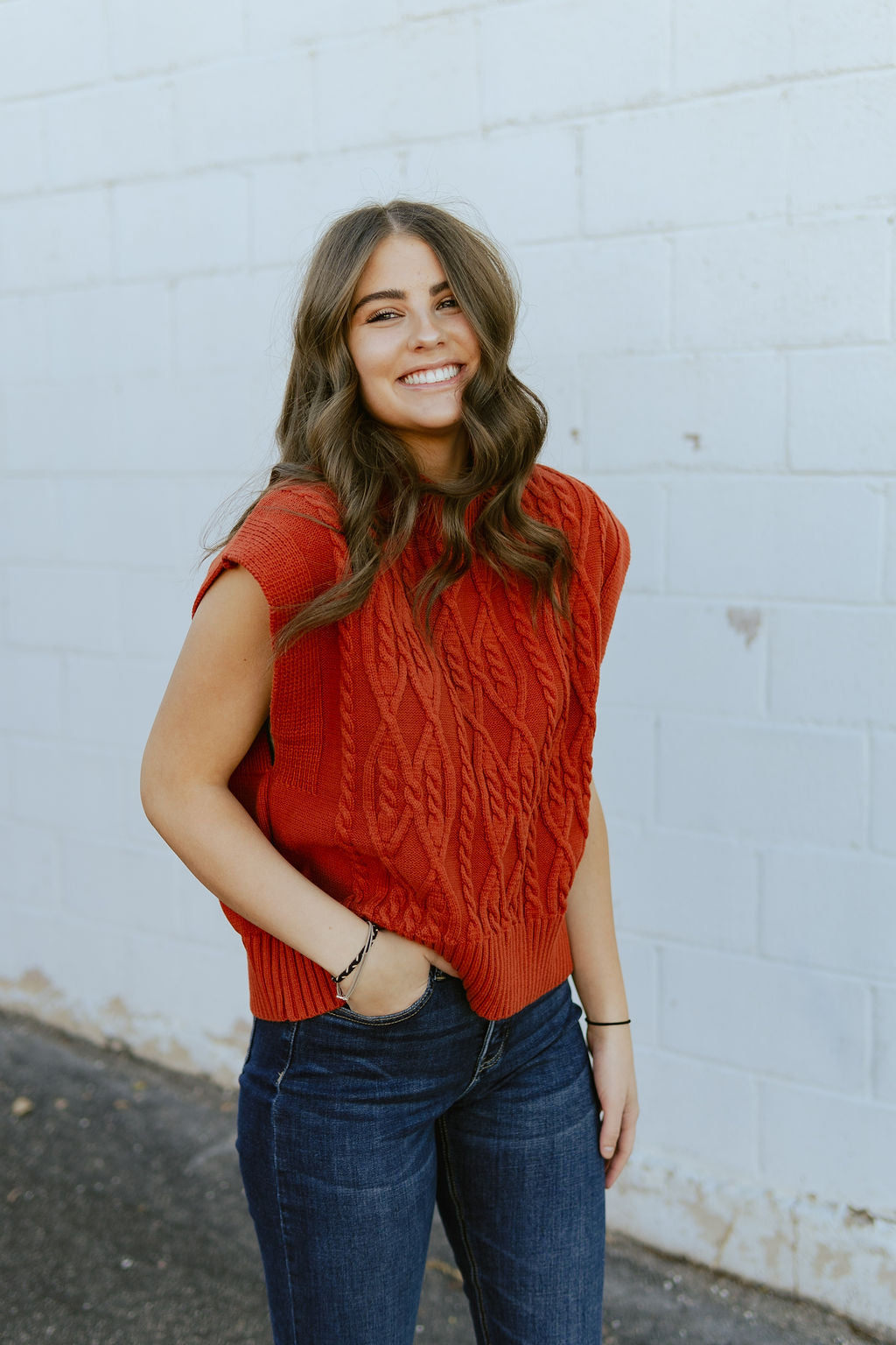 Rust red sleeveless sweater with cable knit texture