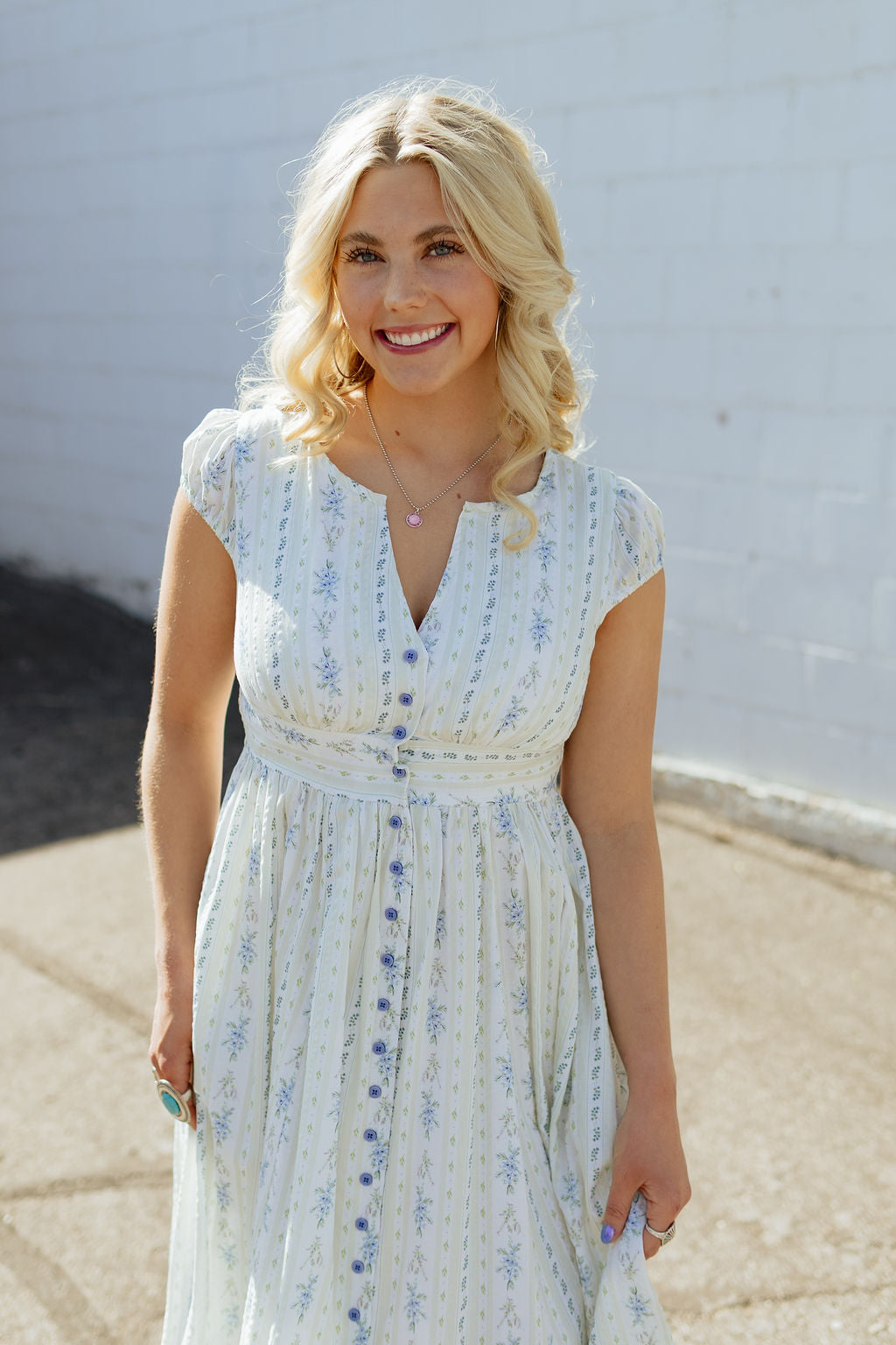 White dress with blue floral and stripe pattern and buttons up the front