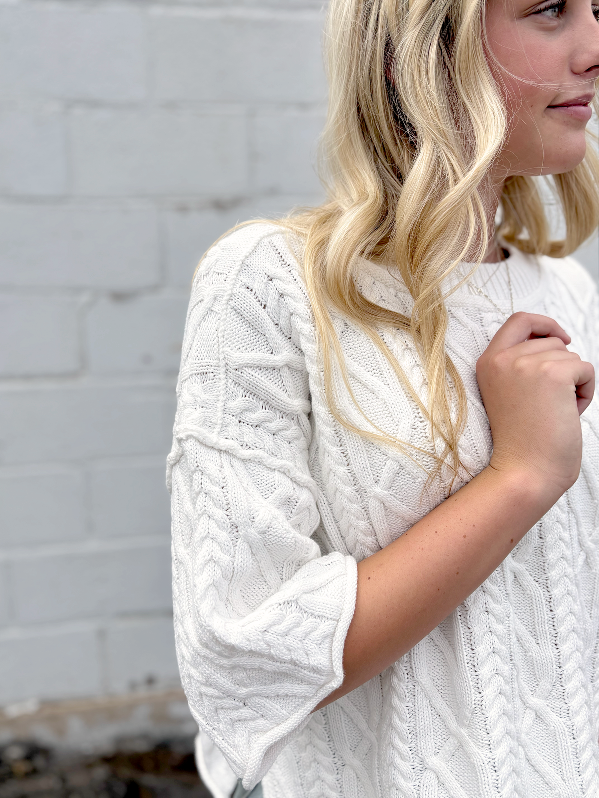 Cute white cropped sweater with short sleeves in a cable knit pattern