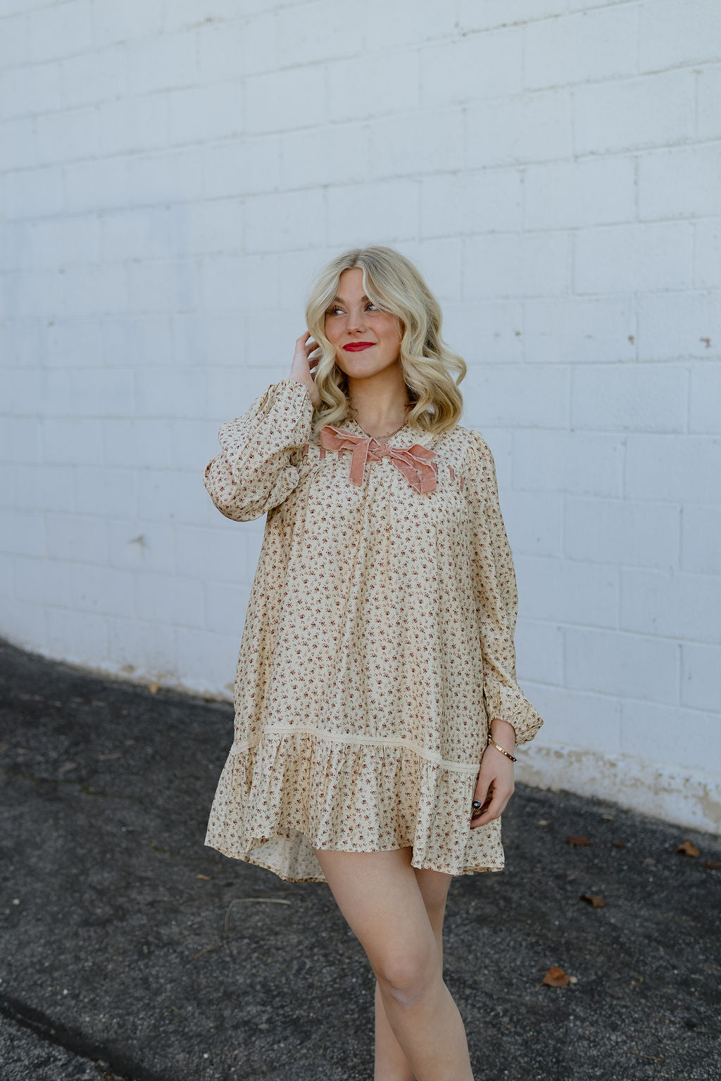 Beige babydoll dress with dark red floral pattern; long in the back and short in the front with velvet bow along neckline