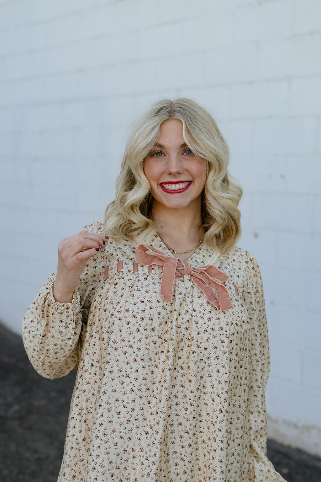 Beige babydoll dress with dark red floral pattern; long in the back and short in the front with velvet bow along neckline